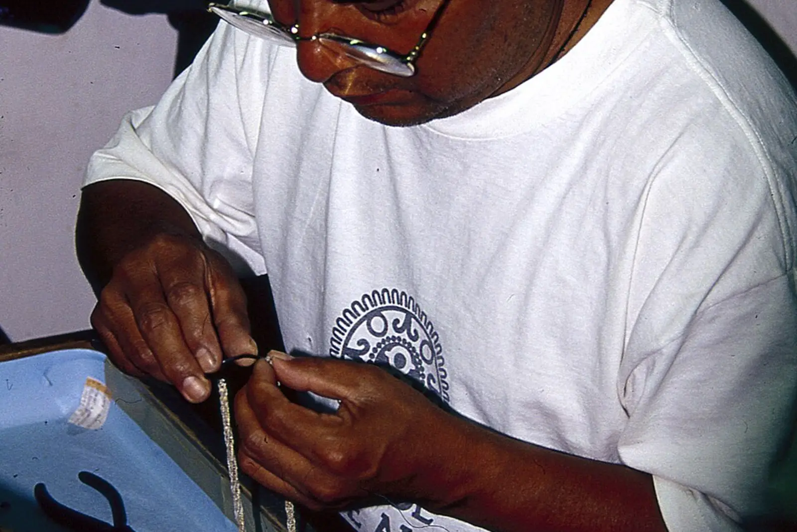 Jewelry artisan assembling a silver necklace by hand at a workshop bench