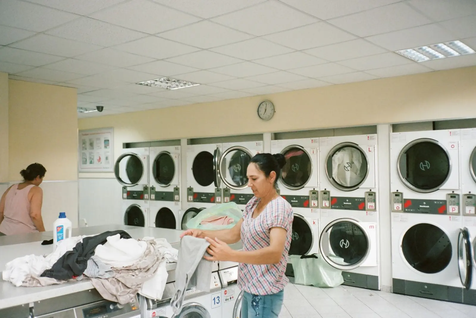 Customer folding laundry inside a real self-service laundromat