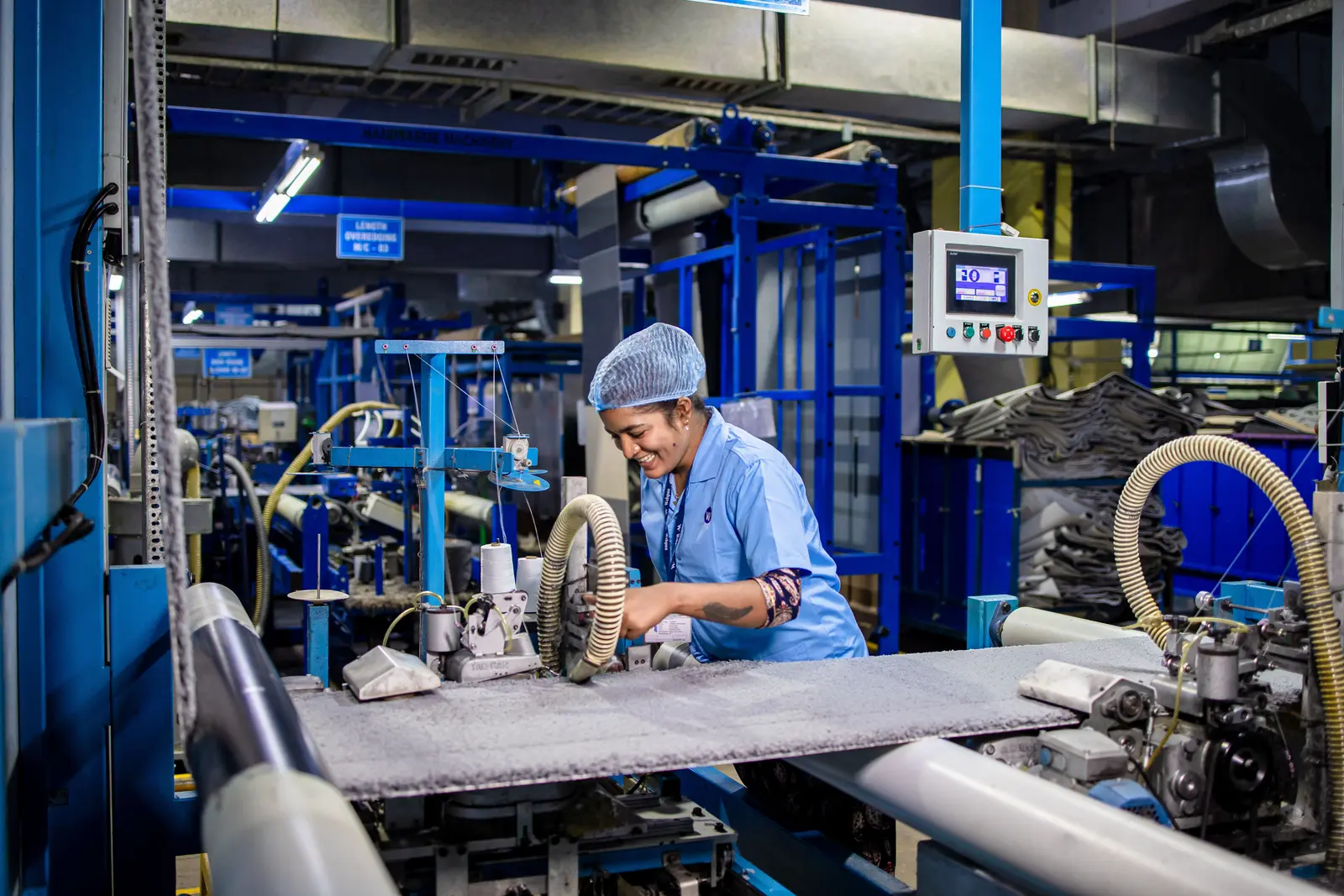 Factory employee operating textile manufacturing equipment on a production floor