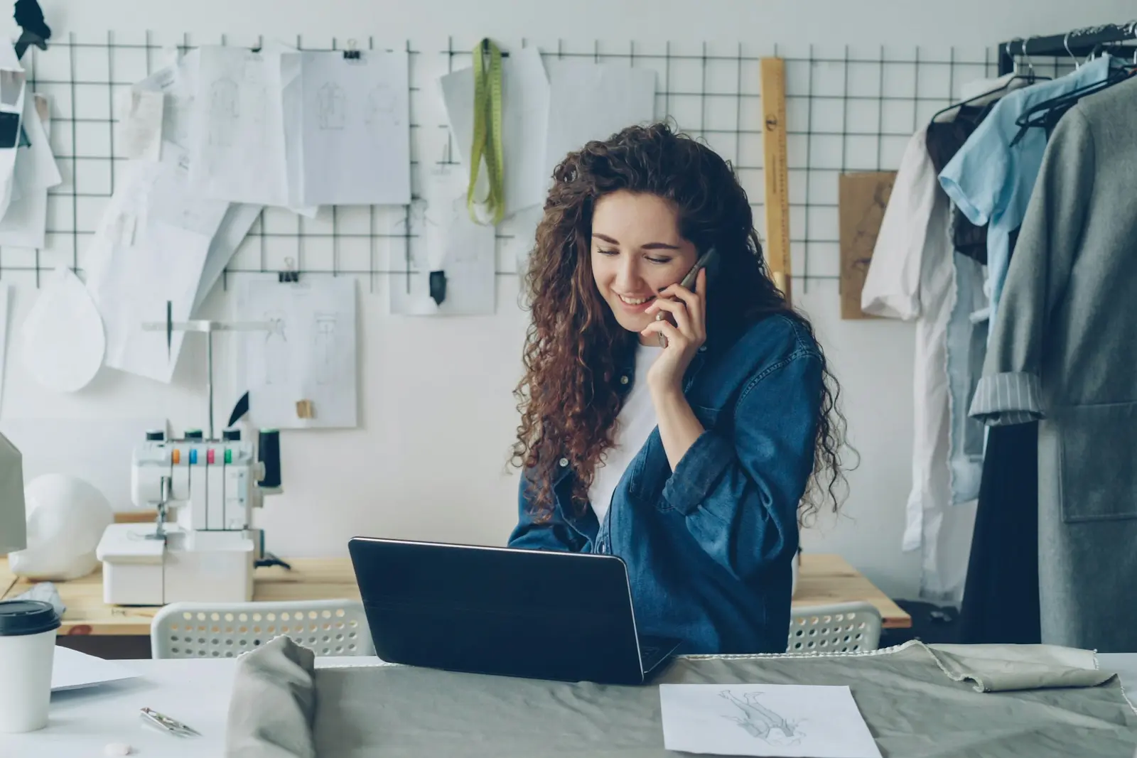 Independent fashion business owner working on a laptop and speaking on the phone