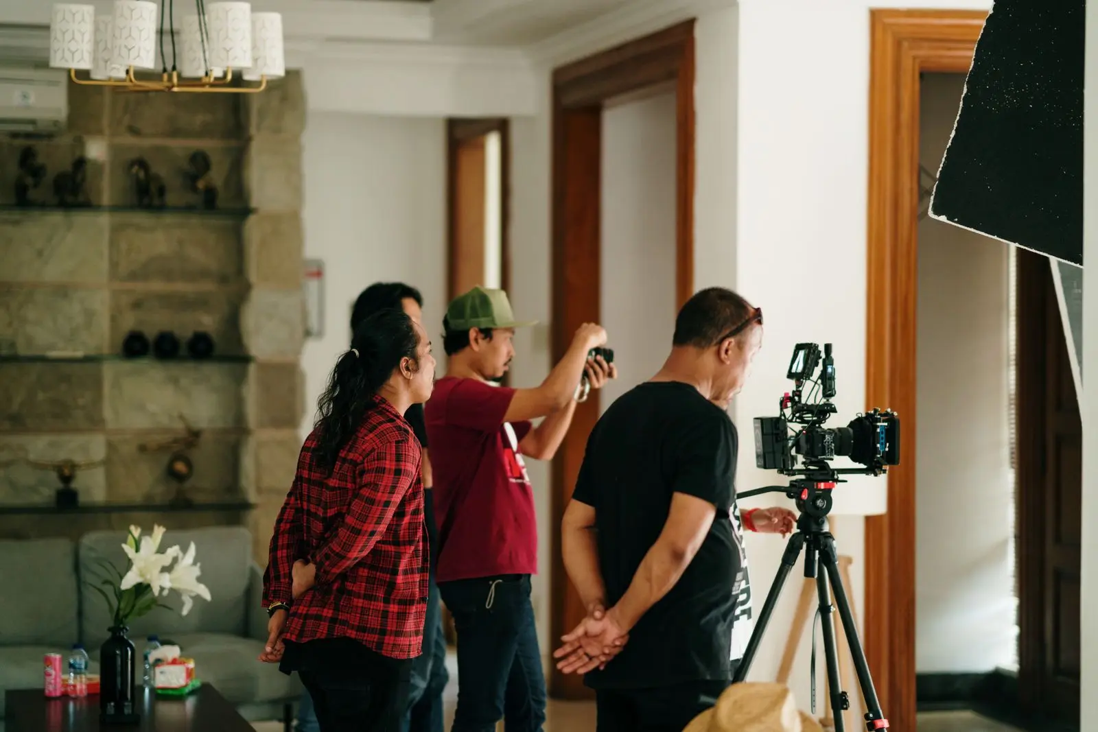 Video production crew operating a cinema camera and lighting inside a home