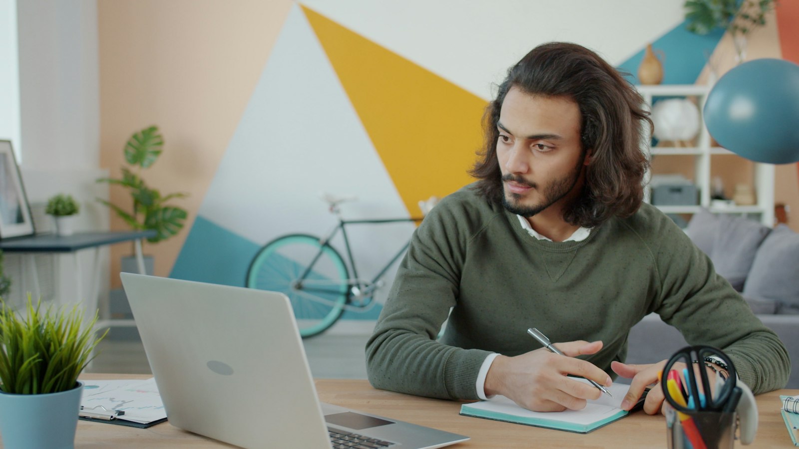 Person planning work beside a laptop and notebook