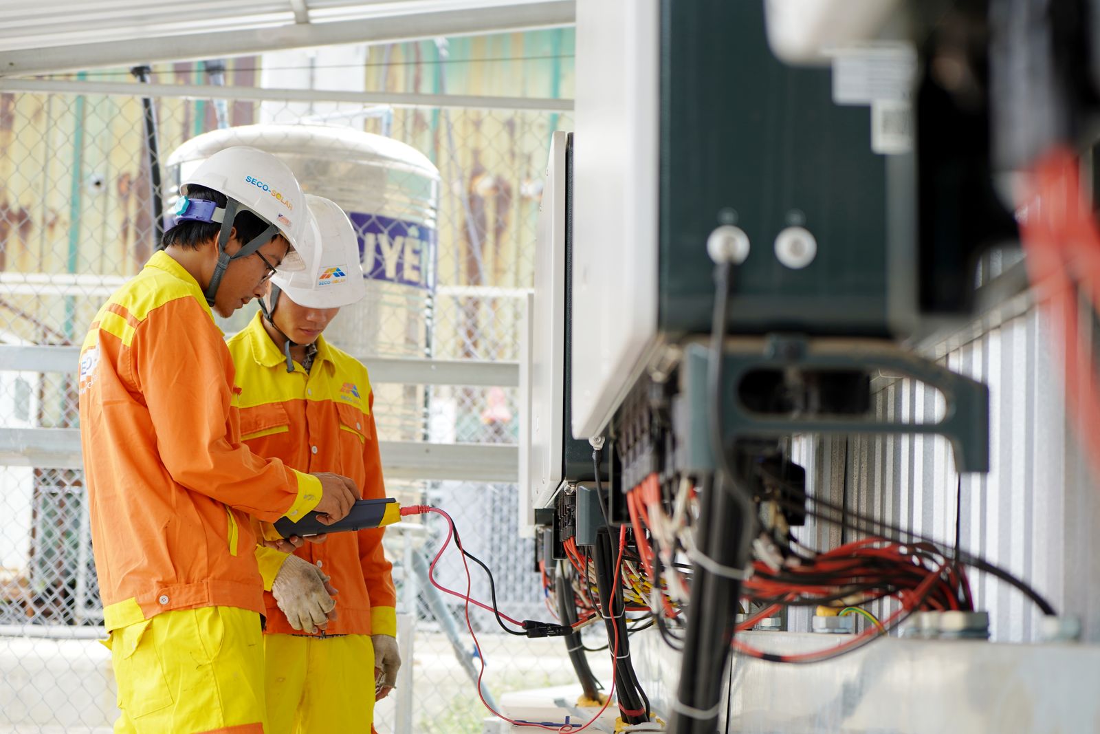 Two electrical professionals checking equipment at a worksite